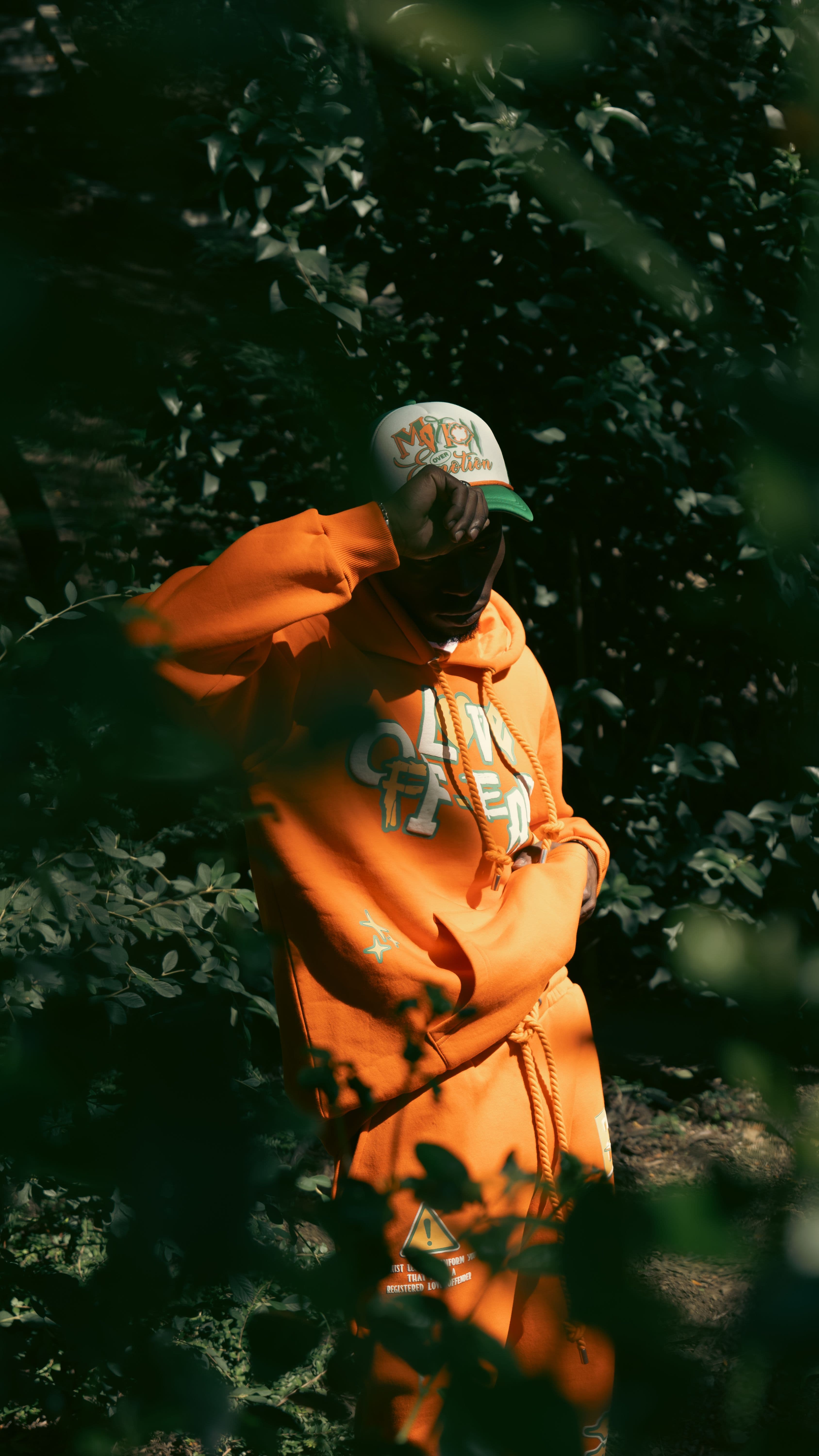 Doğal yeşil fon önünde turuncu streetwear parçalarla model